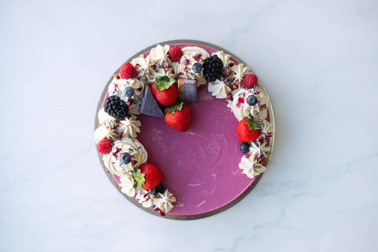 A slice of Berrylicious Cake on a plate showing colourful berry layers and smooth vanilla frosting